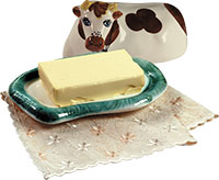 Маслёнка со сливочным маслом и керамическая фигурка коровы. Фото
