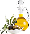 Оливки в тарелочке и графин с оливковым маслом. Фото